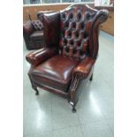 A mahogany and oxblood leather Chesterfield wingback armchair