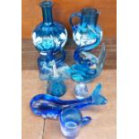 A collection of blue glass items including jugs decorated with flowers, dolphins, etc.