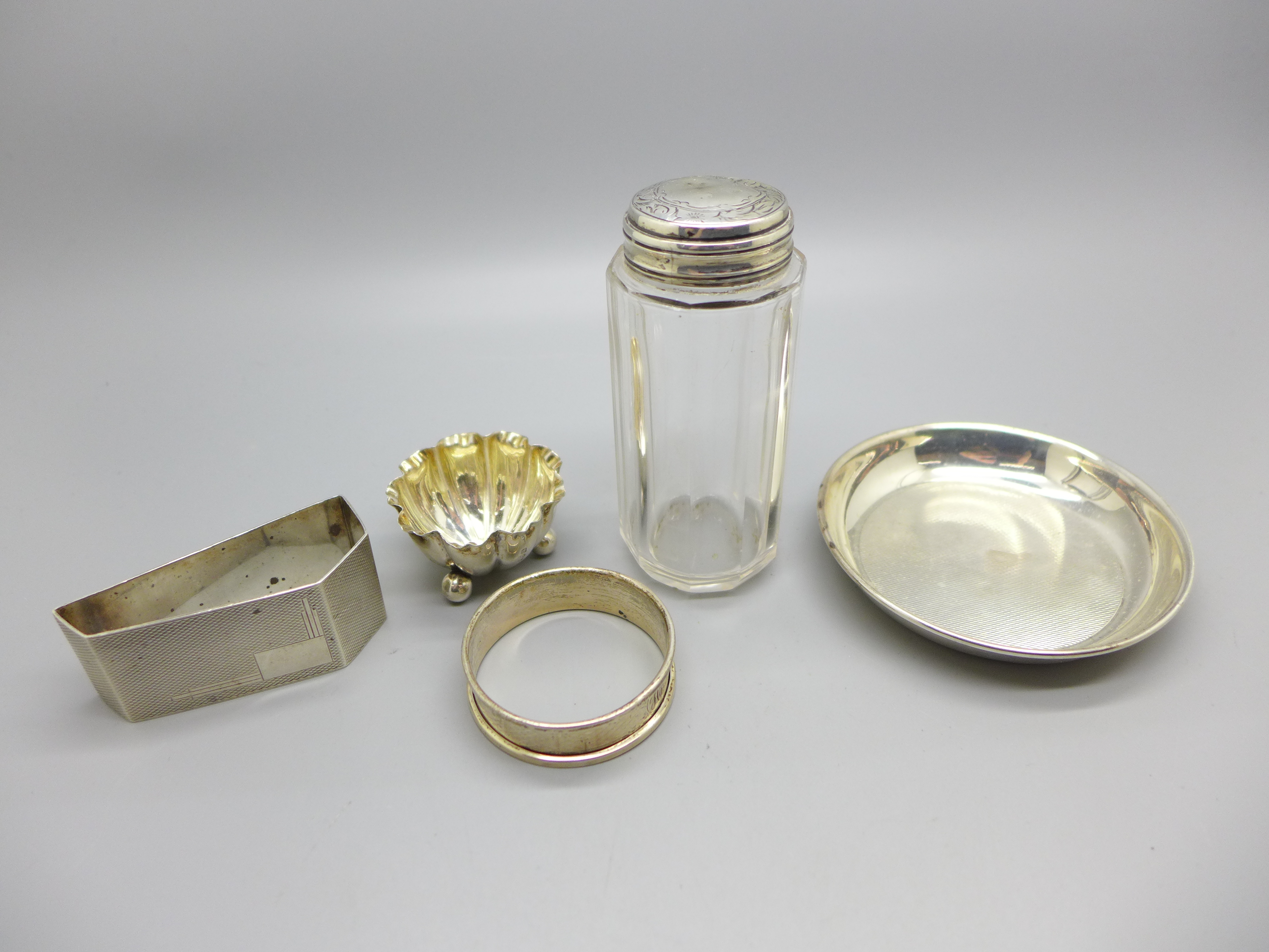 Two silver napkin rings, a Victorian silver salt, a silver dish and a silver topped glass jar, 85g