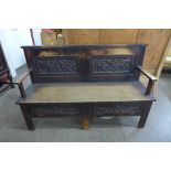 An Arts and Crafts carved oak settle