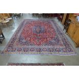 A fine Persian hand knotted red ground Mashad rug, 390 x 290cms