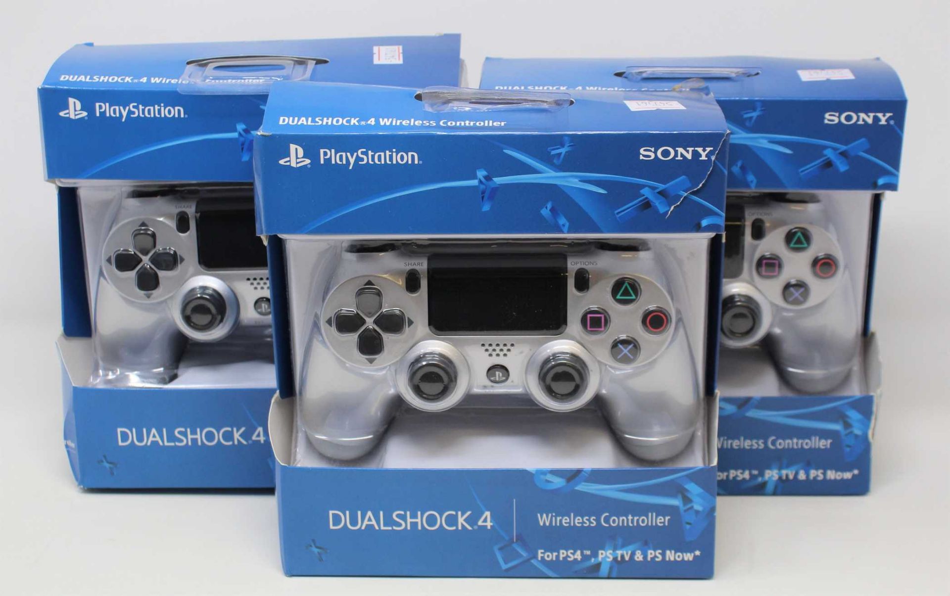 Four boxed as new Sony PlayStation DUALSHOCK 4 Wireless Controllers in Silver (some damage to box).