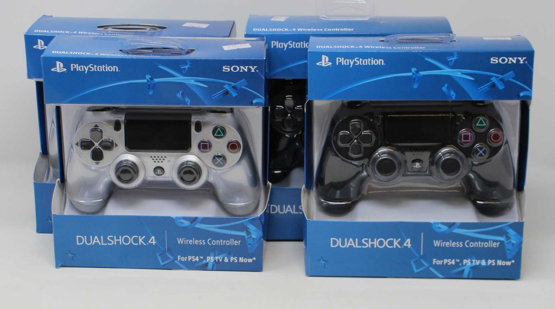 Two boxed as new Sony PlayStation DUALSHOCK 4 Wireless Controllers in Black and two boxed as new