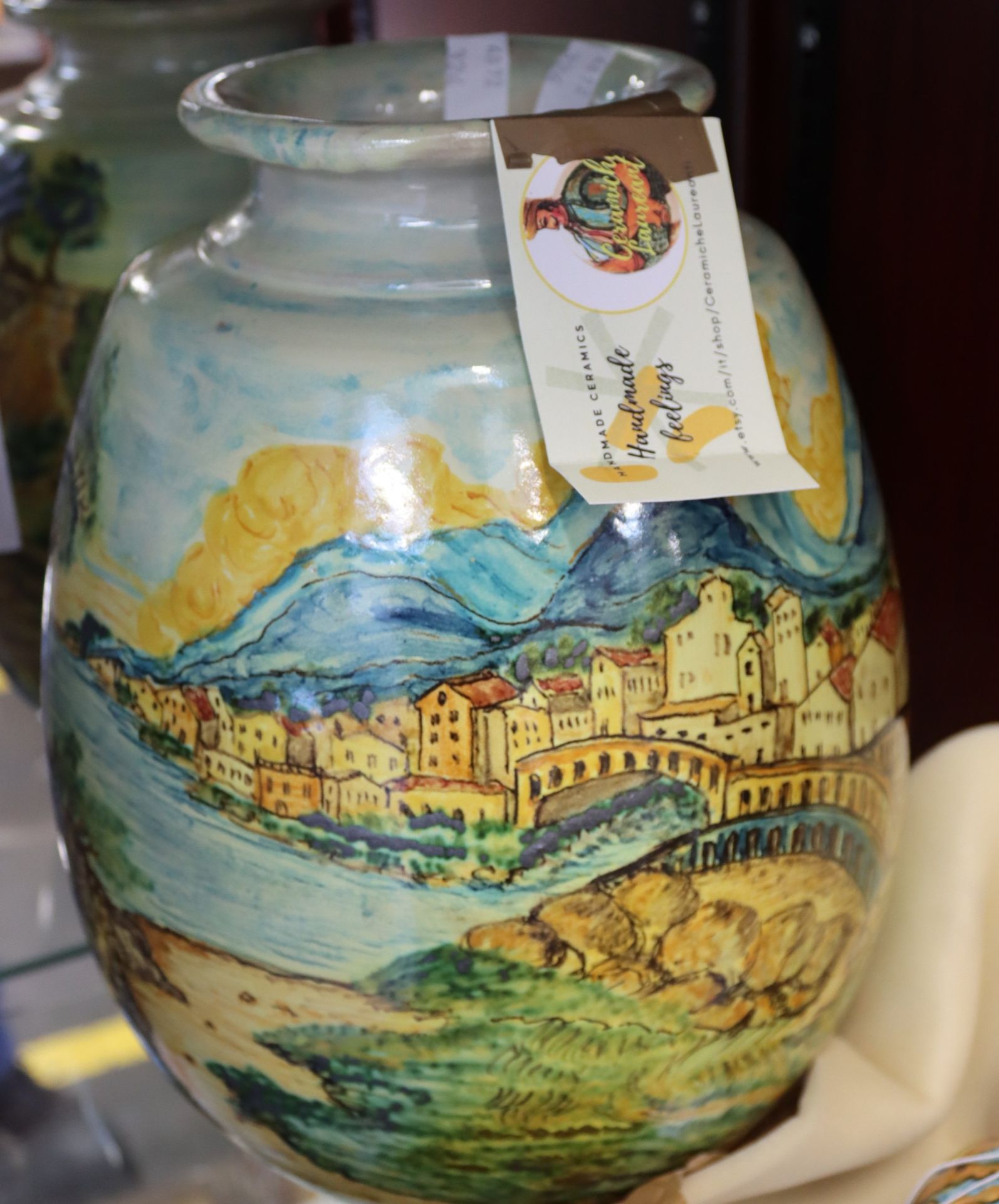 A handmade vase picturing an Italian landscape and a ceramic bauble from Ceramiche Laureanti.