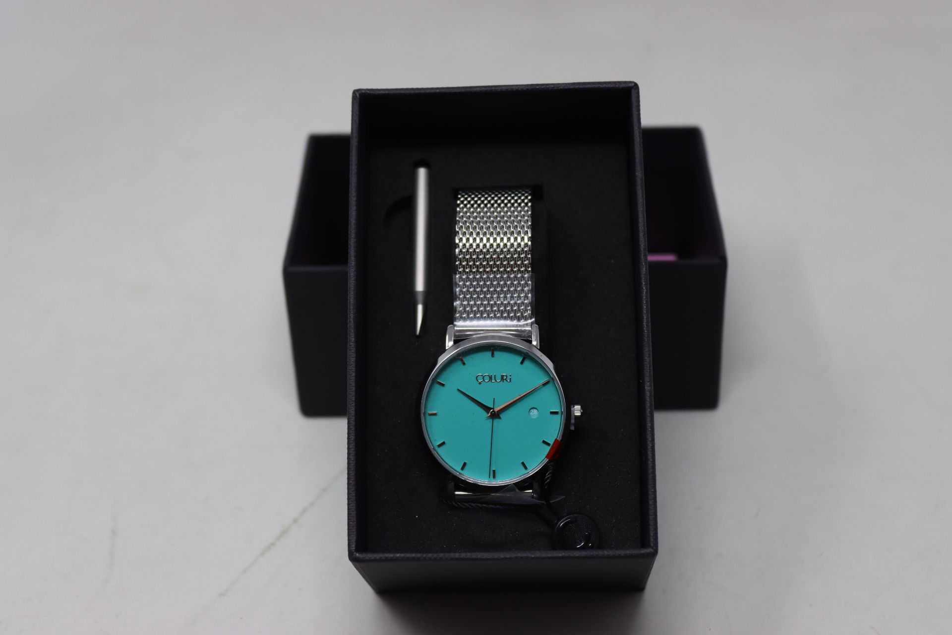 A ladies boxed as new pin-on Coluri Watch in turquoise with a spare strap.