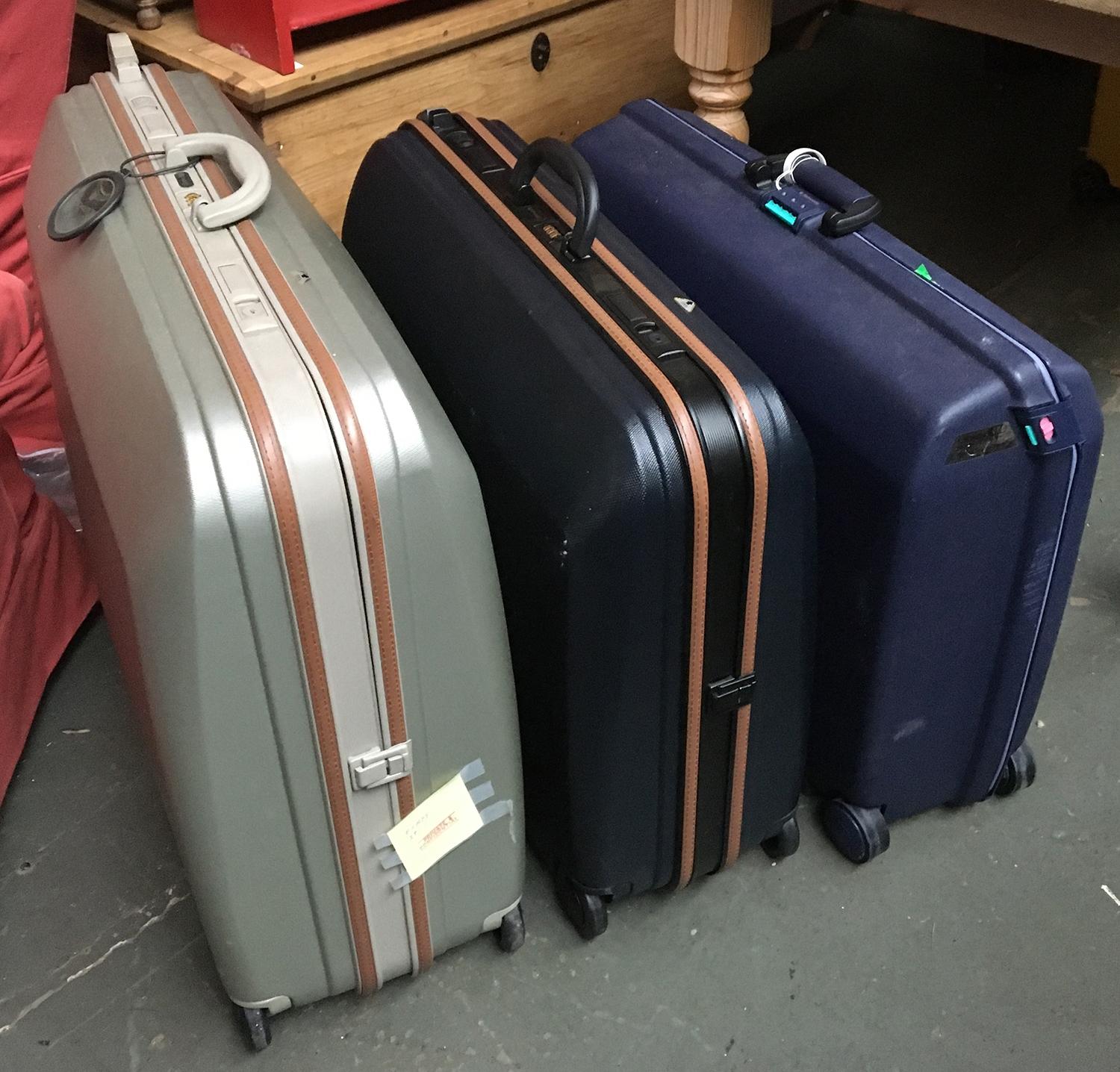 A set of three graduating hard pull-along suitcases; together with two others