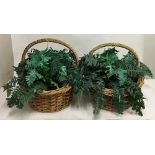 A pair of wicker baskets filled with plastic ferns