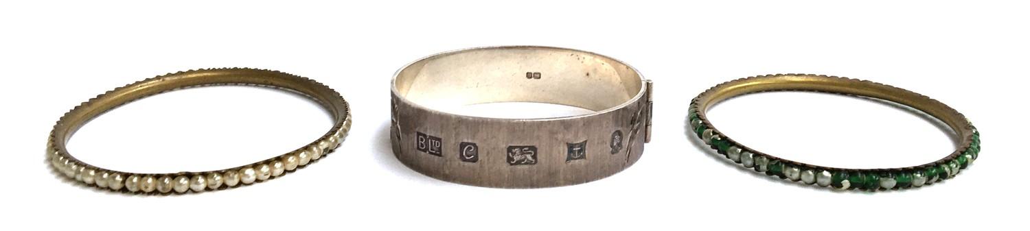 A silver hinged bracelet marked Birmingham 1977, BLtd, with two other bangles