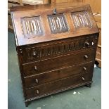 A 20th century oak bureau, linen fold decoration, fall front over four graduating drawers,