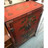 A Oriental red lacquered cupboard, depicting a peacock amongst foliage, two doors with single shelf,