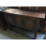 An oak refectory style sideboard, two cupboard doors with rosette and lozenge decoration, on
