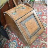An oak coal scuttle, with decorative panel front, brass carry handle and liner present