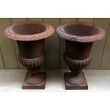 A pair of small cast iron garden urns, half gadrooned, on square plinth bases, each 23x33.5cm