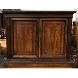 A small cupboard, two panelled doors on plinth base, with single glass shelf, bears plaque for