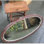 An oval wall mirror with bevelled glass, overall dimensions 87.5x48cm; together with a wooden step