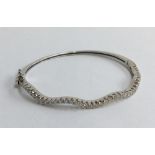18ct white gold and diamond bracelet in the form of a hinged bangle. One side is set with approx.
