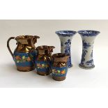 A graduating set of three lustre jugs, the largest jug 18cmH; together with two blue and white