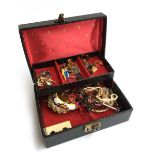 Black jewellery box containing various items of costume jewellery to include a budgerigar brooch and