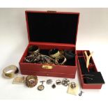 Red jewellery box containing costume jewellery to include a rolled gold bangle, further bangles,