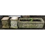 A pair of composite stone plinths, each 32cmH, together with a trough planter depicting cherubs,