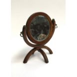 A small circular adjustable mirror on foldable stand, the back with glazed embroidery worked in gilt