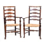 A near pair of ash and elm ladderback armchairs, with flat topped arms, rush seats and turned legs
