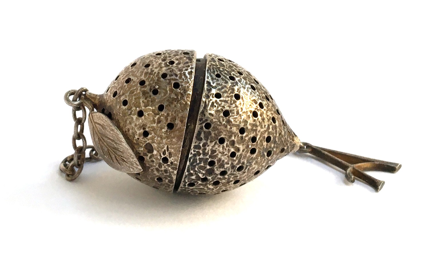 An Asprey & Co Ltd silver tea strainer/pomander, in the form a lemon with single leaf, in two