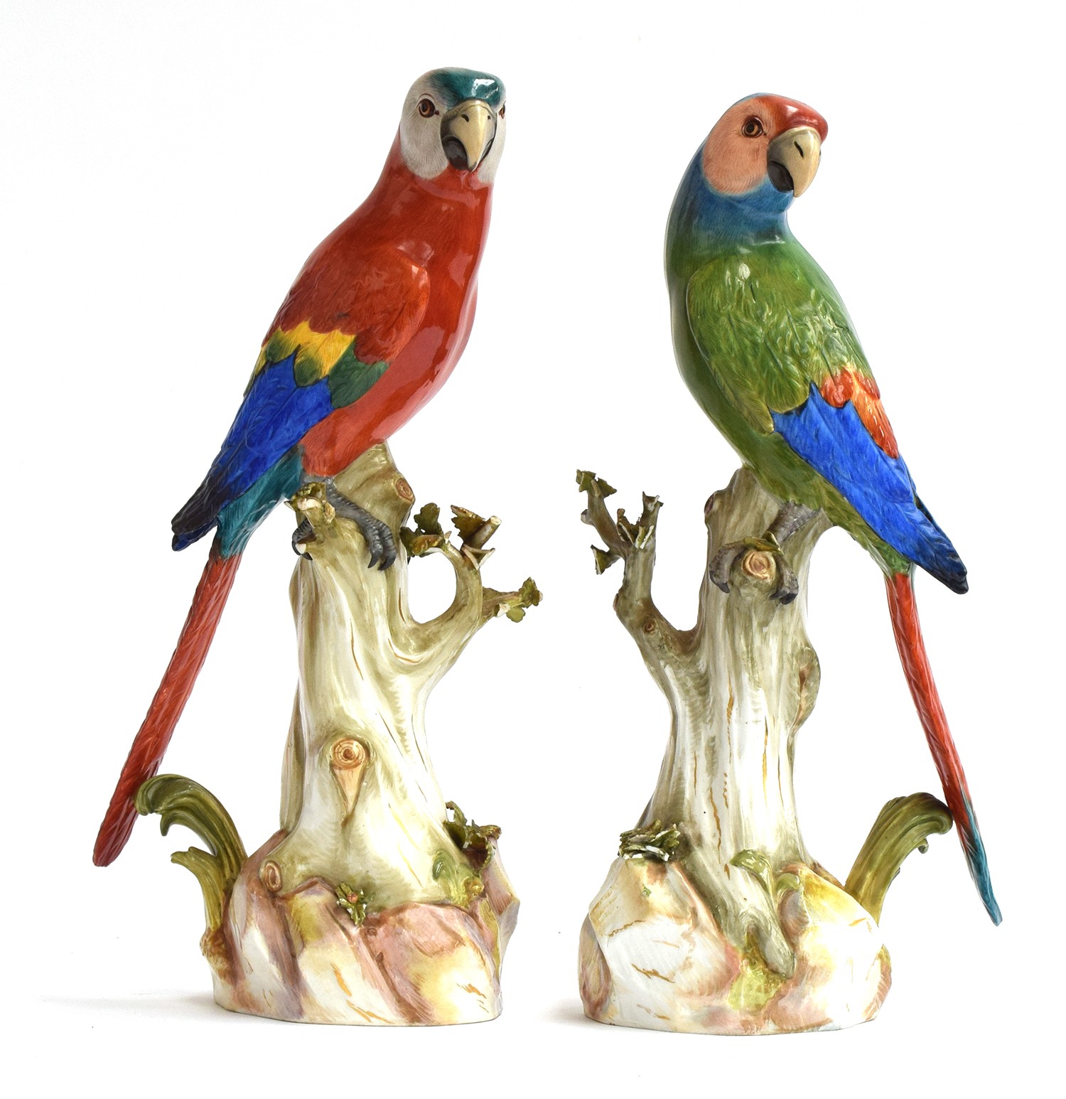 A pair of late 19th century Meissen parrots with colourful plumage perched upon tree stumps, first