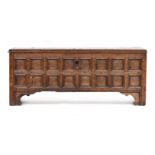 A late 17th/early 18th century oak coffer, the front comprising 16 panels, with candle box