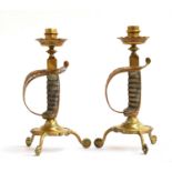 A pair of brass candlesticks formed with Victorian sword hilts with shagreen and wire grips,