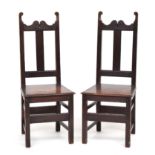 A pair of provincial oak hall chairs, shaped top rail over a solid moulded seat, on square section