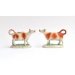 A pair of 19th century Staffordshire cow creamers (af), horns heightened in gilt, standing four