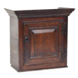 An early 18th century oak wall cabinet, fielded panel door opening to reveal three drawers, 59cm