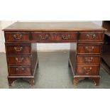 A kneehole desk, with green leather skiver over the traditional arrangement of nine drawers, on