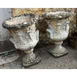 A pair of composite stone garden urns, decorated with prancing figures, 55cmH
