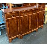 A reproduction breakfront sideboard, crossbanded top over three drawers (the central drawer with