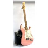 A pink Squire by Fender stratocaster electric guitar; together with a Squire SP10 guitar amp