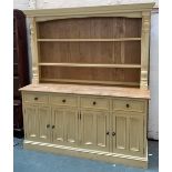 An oak and pine kitchen dresser painted a pale yellow, the upper section two shelves, flanked by