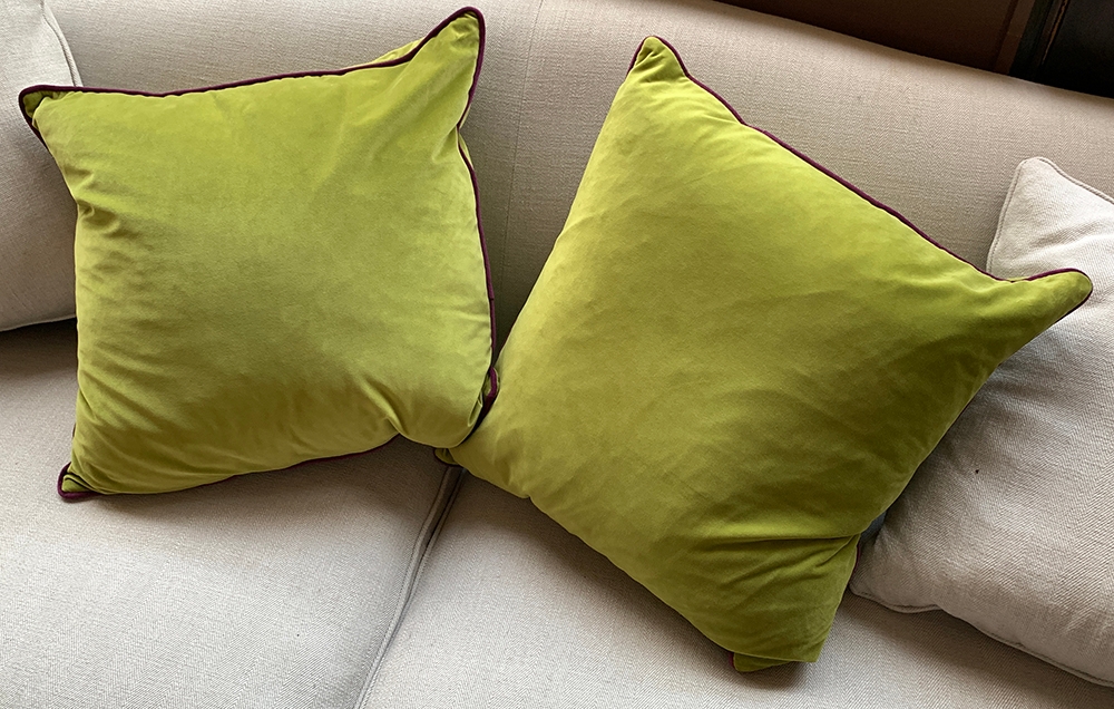 A pair of green velvet cushions, with purple piping, approx. 50cm2