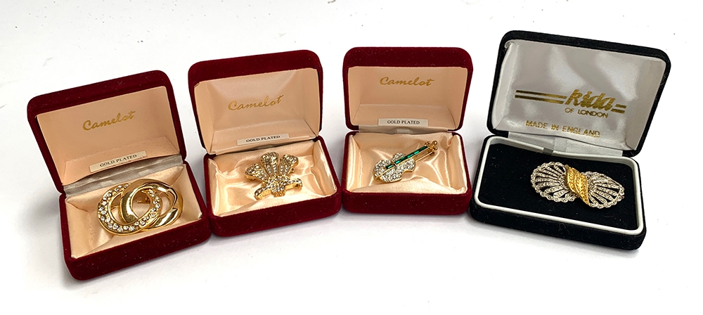 Three Camelot brooches, yellow metal set with faux diamonds, in the form of a fleur de lys,