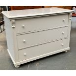 A white painted chest of three drawers, the drawers flanked by acanthus detail and moulding,