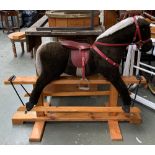 A vintage rocking horse with leather saddle and bridle, on a pine base