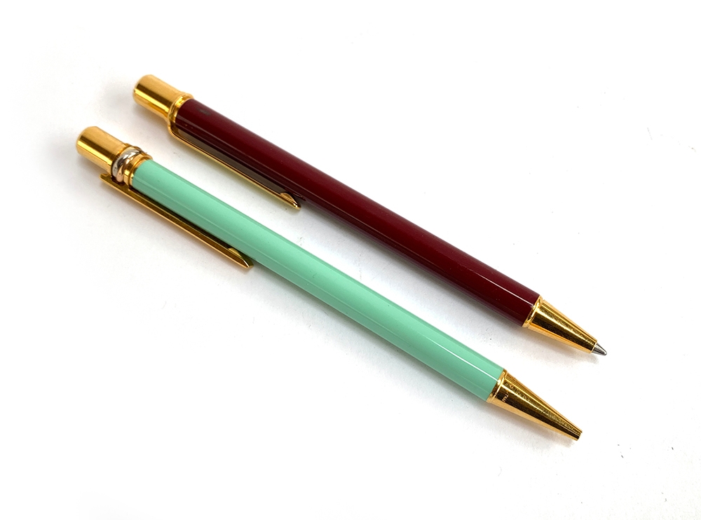 Two Must de Cartier ballpoint pens, with twist action, in maroon and cyan (2)