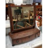 A Regency adjustable dressing mirror on fluted supports, over a bow front base of three drawers