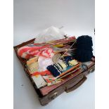 A small vintage travel case containing a number of knitting patterns, needles, wool etc