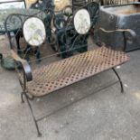 A wrought iron folding garden bench with lattice seat