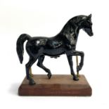 A painted figure of a horse, mounted on a wooden plinth, 26cm high