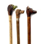 Three walking sticks, with carved knops depicting pheasant, dog, and fox, each with glass eyes (3)