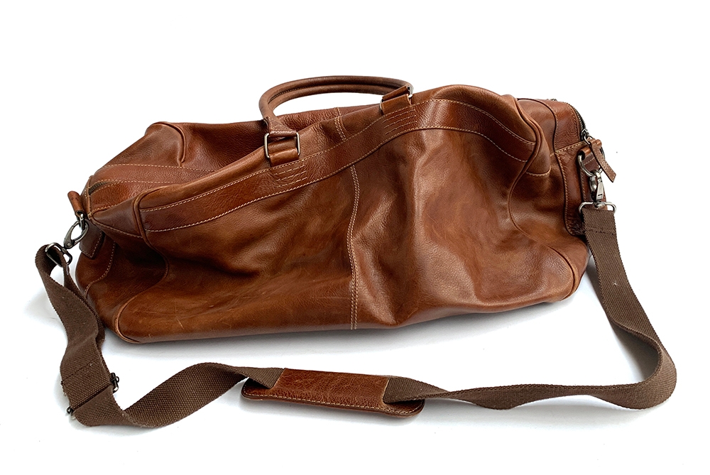 A brown leather duffel bag with interior pockets and shoulder strap