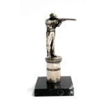 A silver plated shotgun shooting trophy, modelled as a marksman on a plinth with laurel frieze, on